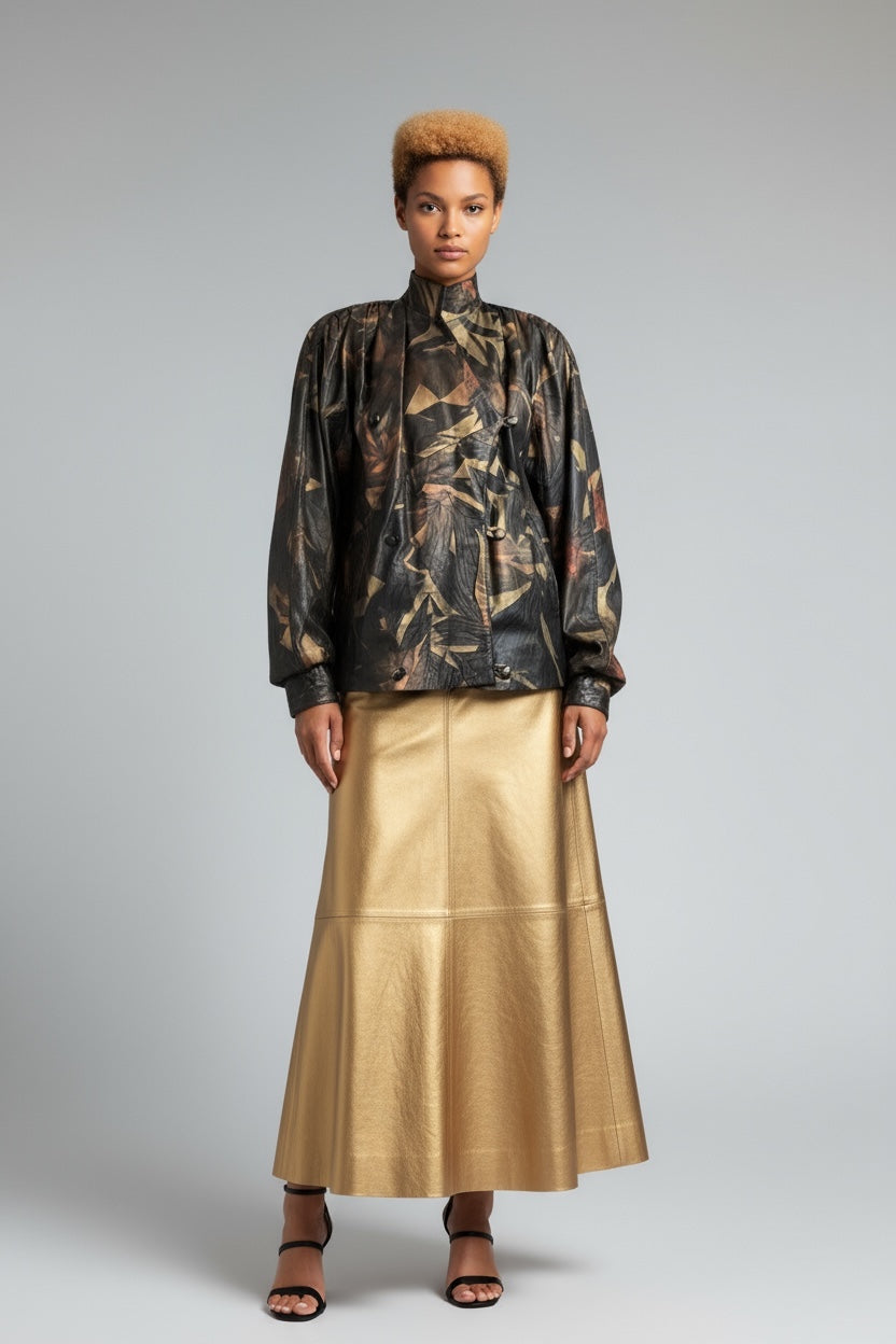 Model wearing a patterned top and gold skirt on a gray background