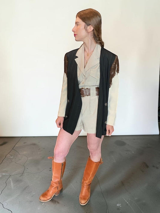 LaliSimone Ozbek striped jacket with fringe detail over a tan safari-style romper and brown boots.