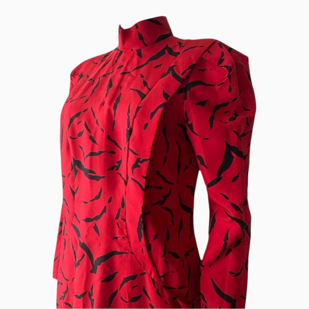 A red long-sleeve blouse with a high mock neck and an abstract black brushstroke pattern, shown on a plain white background.