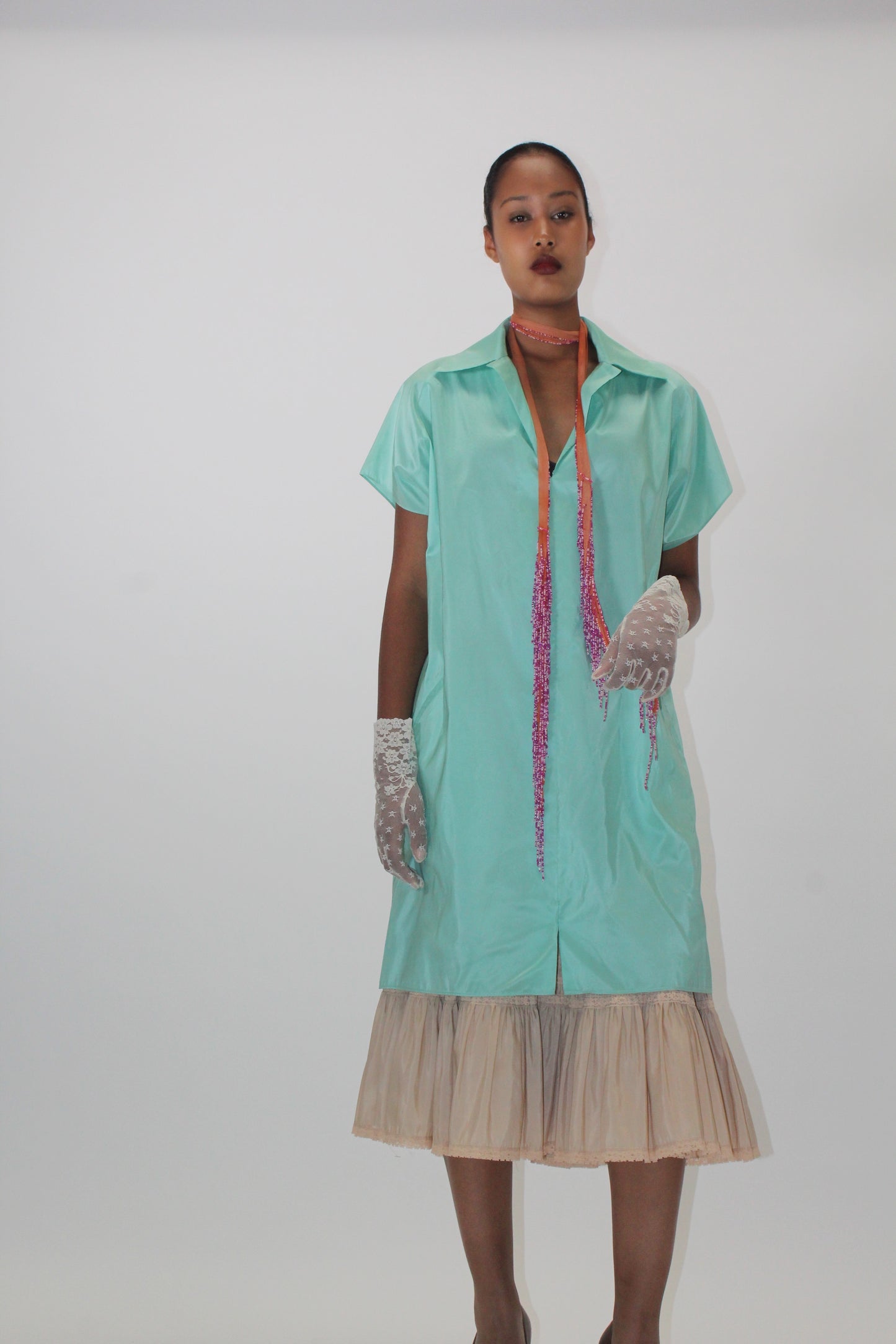 Model wearing the Chan Luu salmon silk beaded fringe scarf tied short at the neck, styled with a mint green shirt dress and tulle skirt