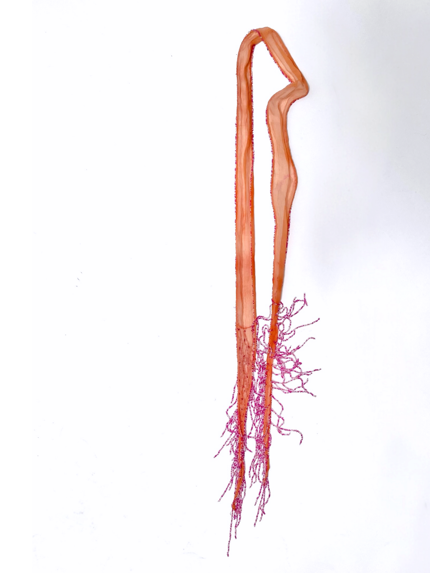 Chan Luu salmon silk scarf folded and hung, showing long pink beaded fringe tassels at the hem