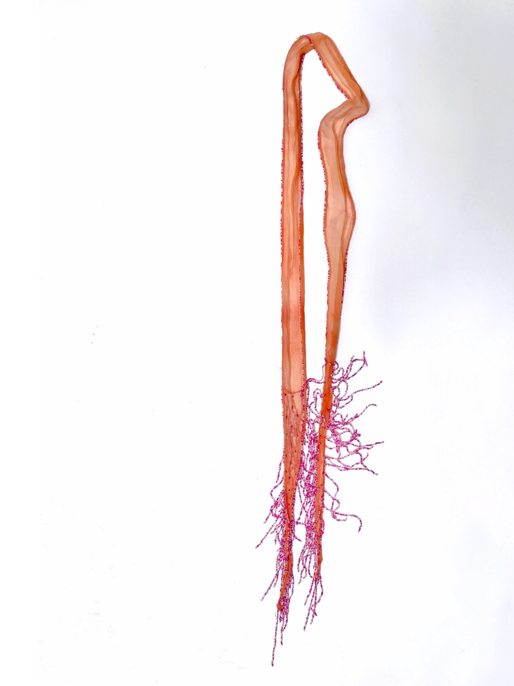 Chan Luu salmon silk scarf folded and hung, showing long pink beaded fringe tassels at the hem
