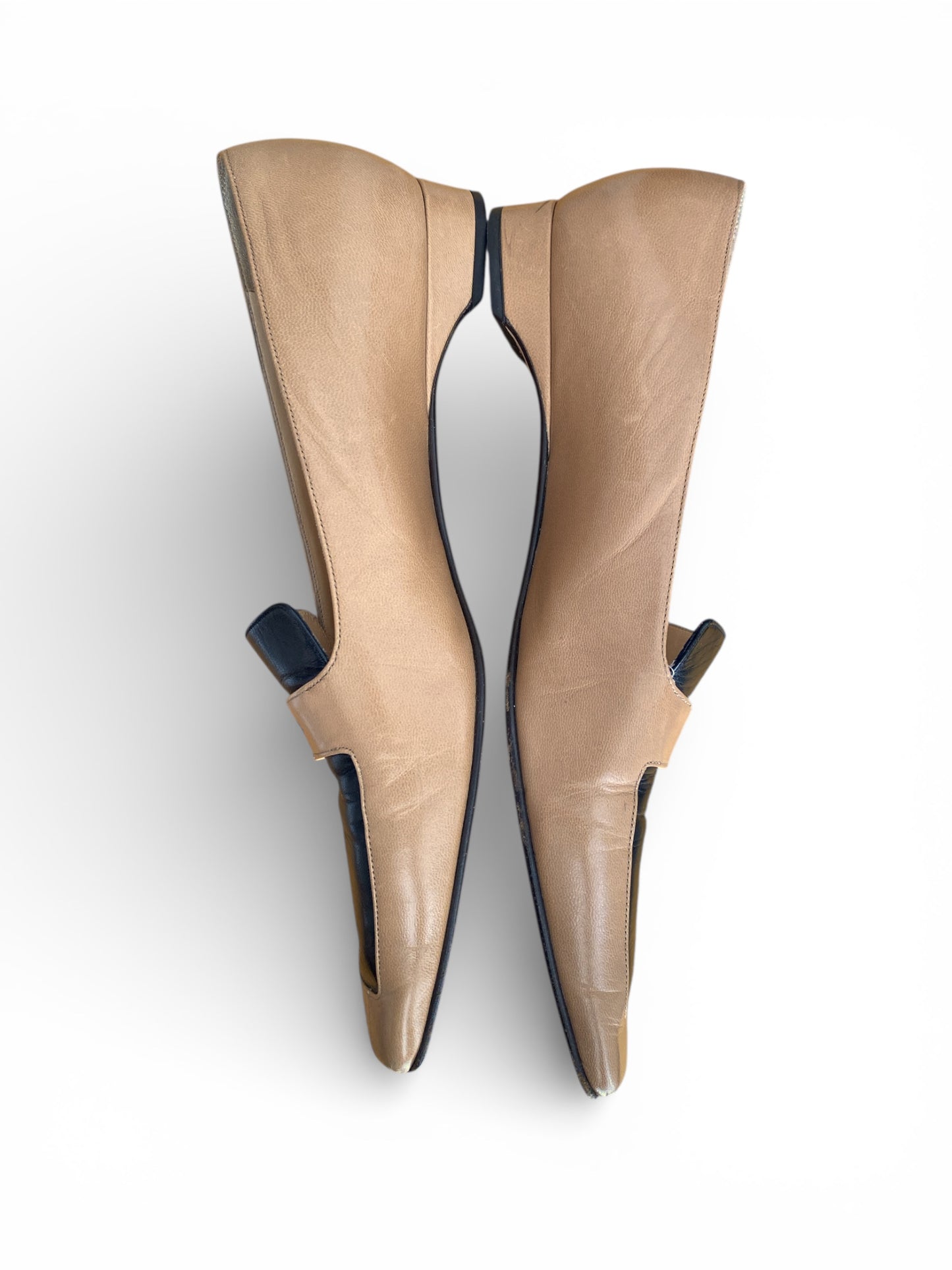 Pair of Chanel beige low-heeled shoes on a white background laying side by side.