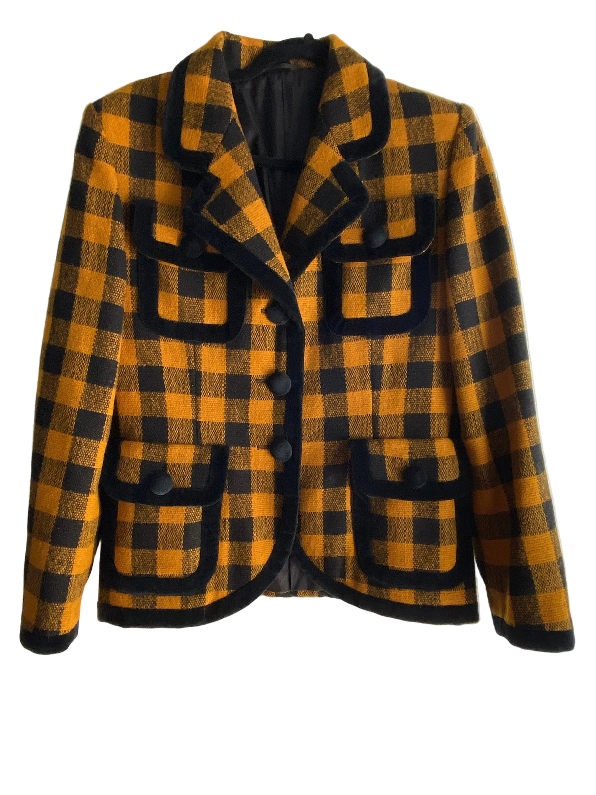 A vintage plaid coat in mustard yellow and black, laid flat on a white paneled surface. The coat features a double-breasted design with large decorative flap pockets and black trim.