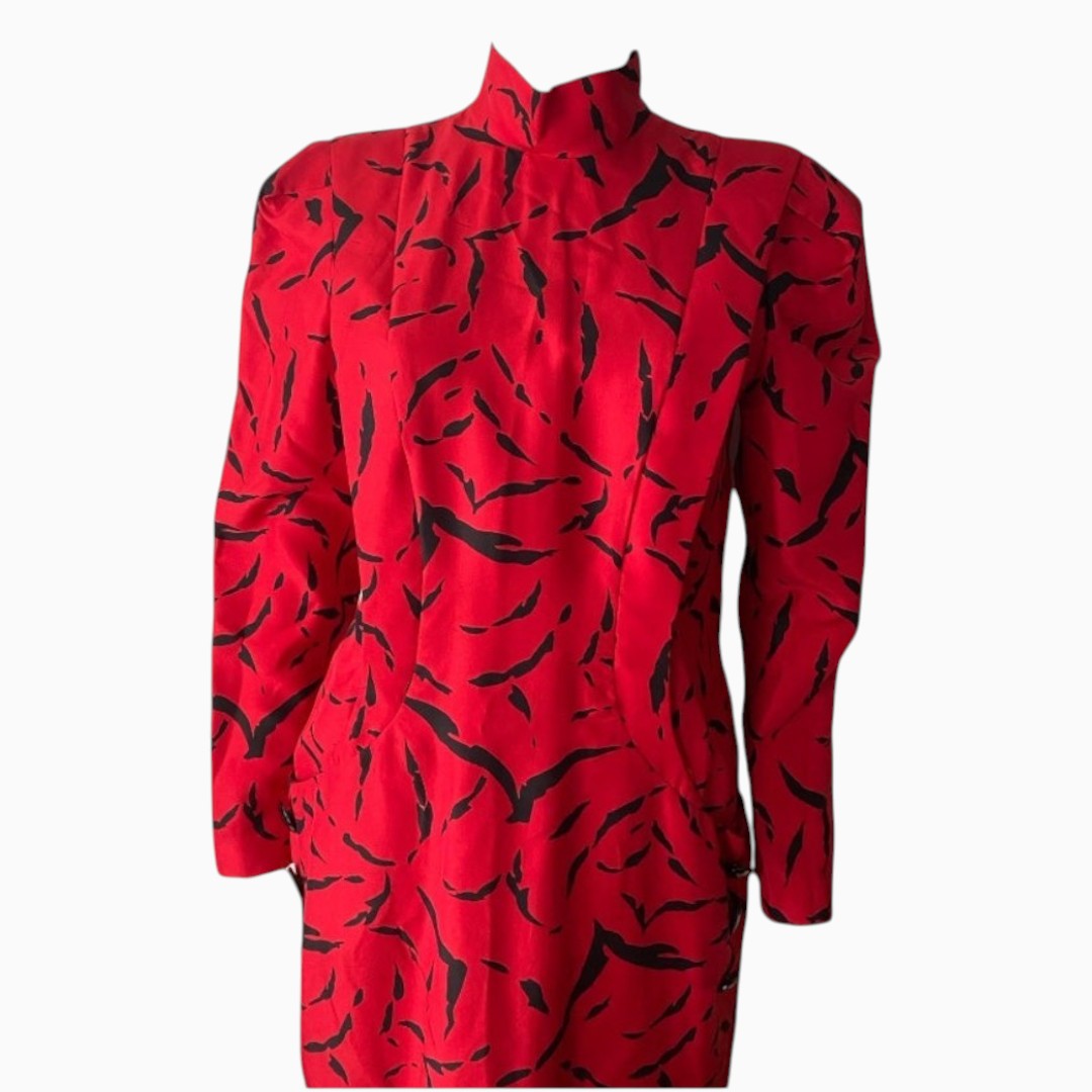 A red long-sleeve blouse with a high mock neck and an abstract black brushstroke pattern, shown on a plain white background.