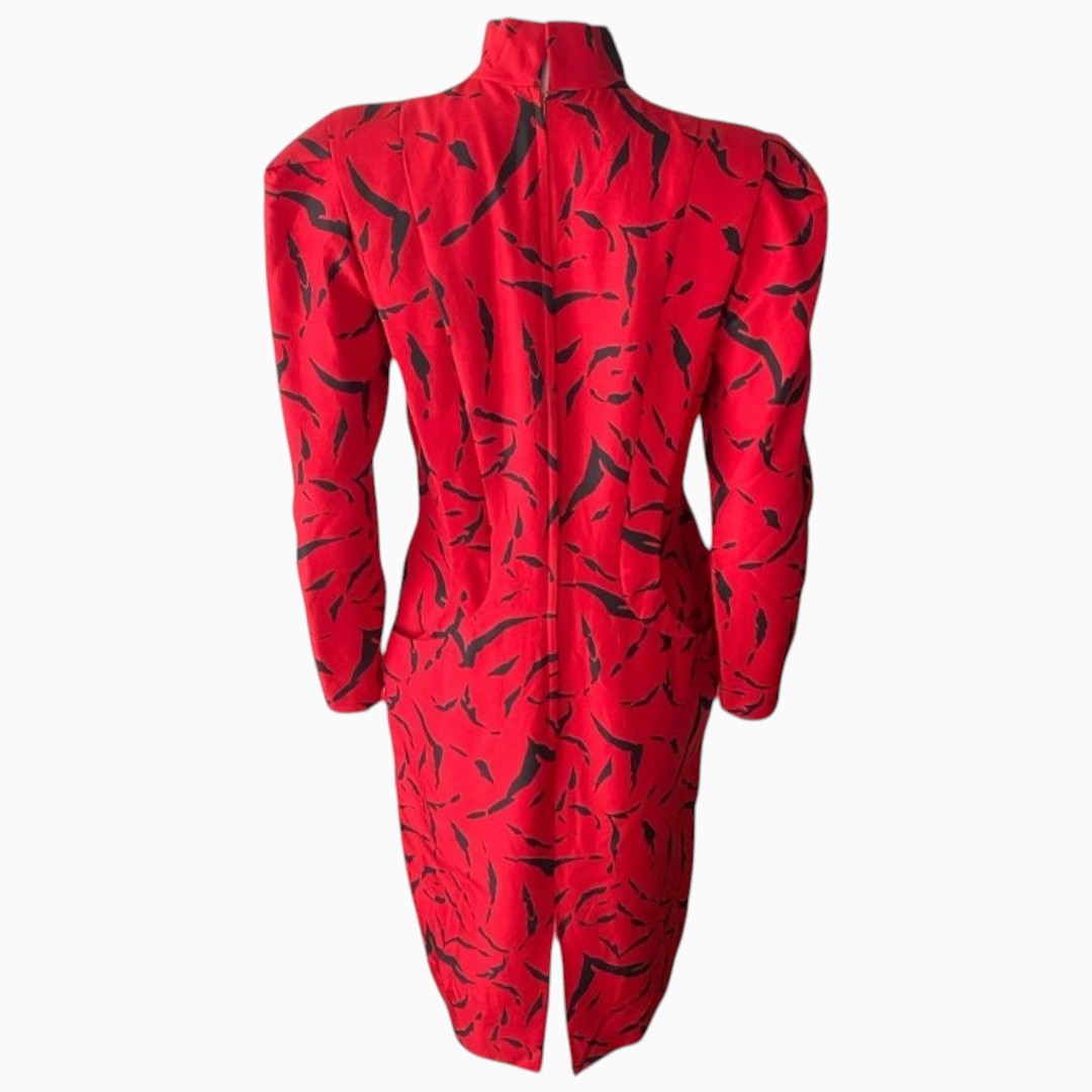 A red long-sleeve jumpsuit with a high mock neck and an abstract black brushstroke pattern, shown from the back against a light gray background.