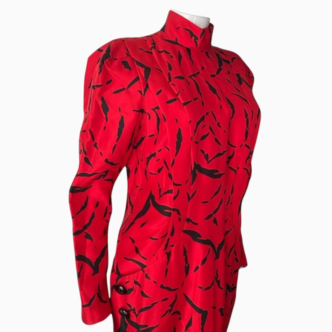 A vibrant red long-sleeve shirt with a black abstract pattern, displayed on a white mannequin torso against a light gray background.