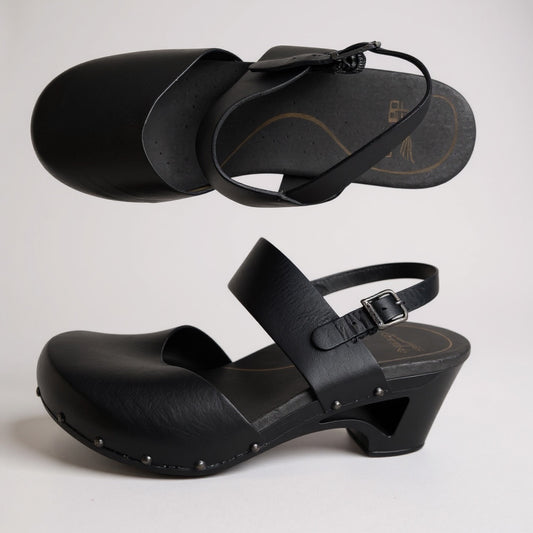 Black wooden clog sandals with straps on a light gray background