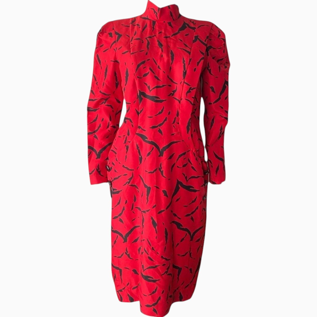 A red long-sleeve dress with a black abstract floral or brushstroke pattern, featuring a high mock neck and structured shoulders, shown against a plain white background.