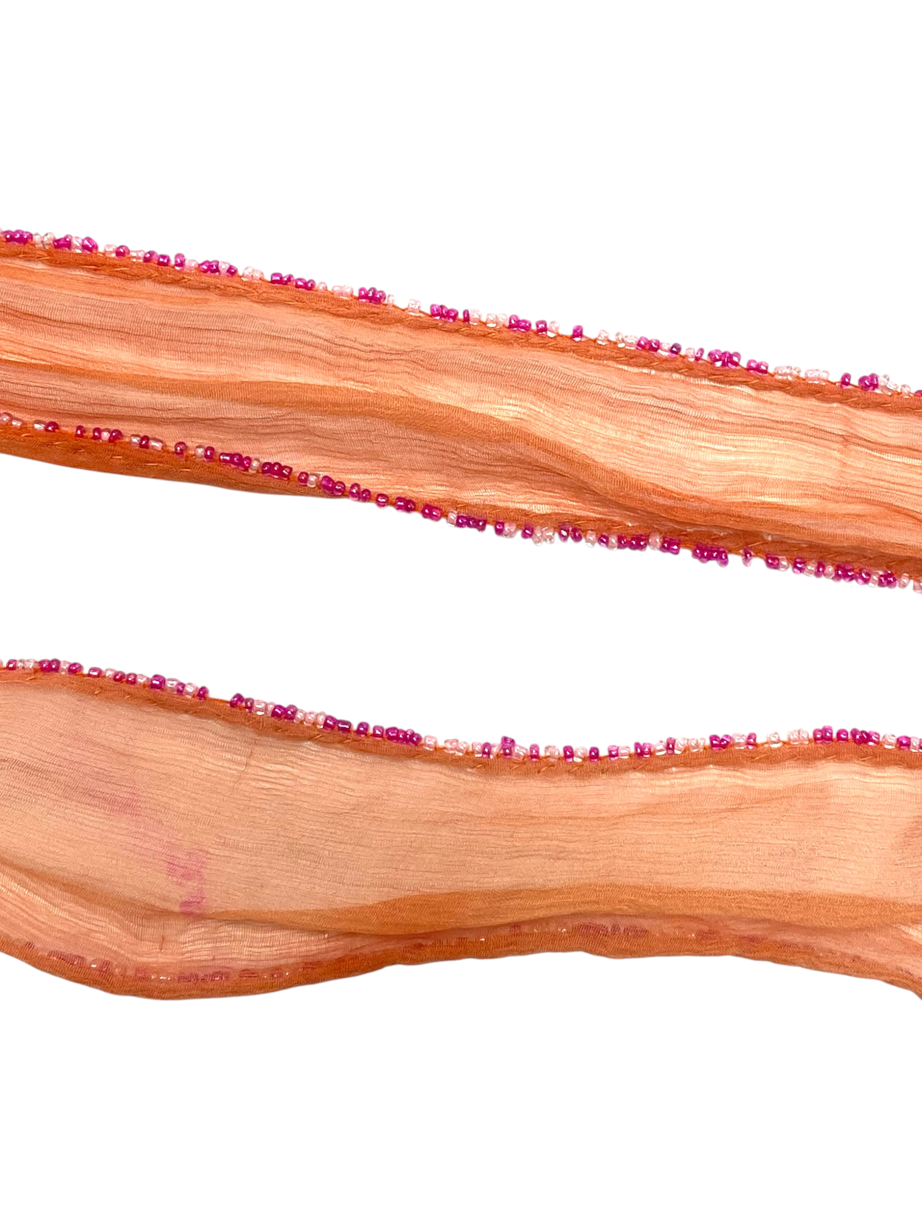 Close-up of Chan Luu scarf's textured salmon silk fabric and fringe
