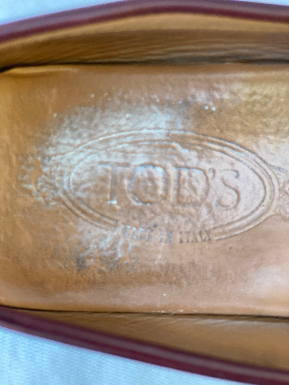 Close-up of the Tod's Made in Italy stamp on the tan leather insole of a loafer