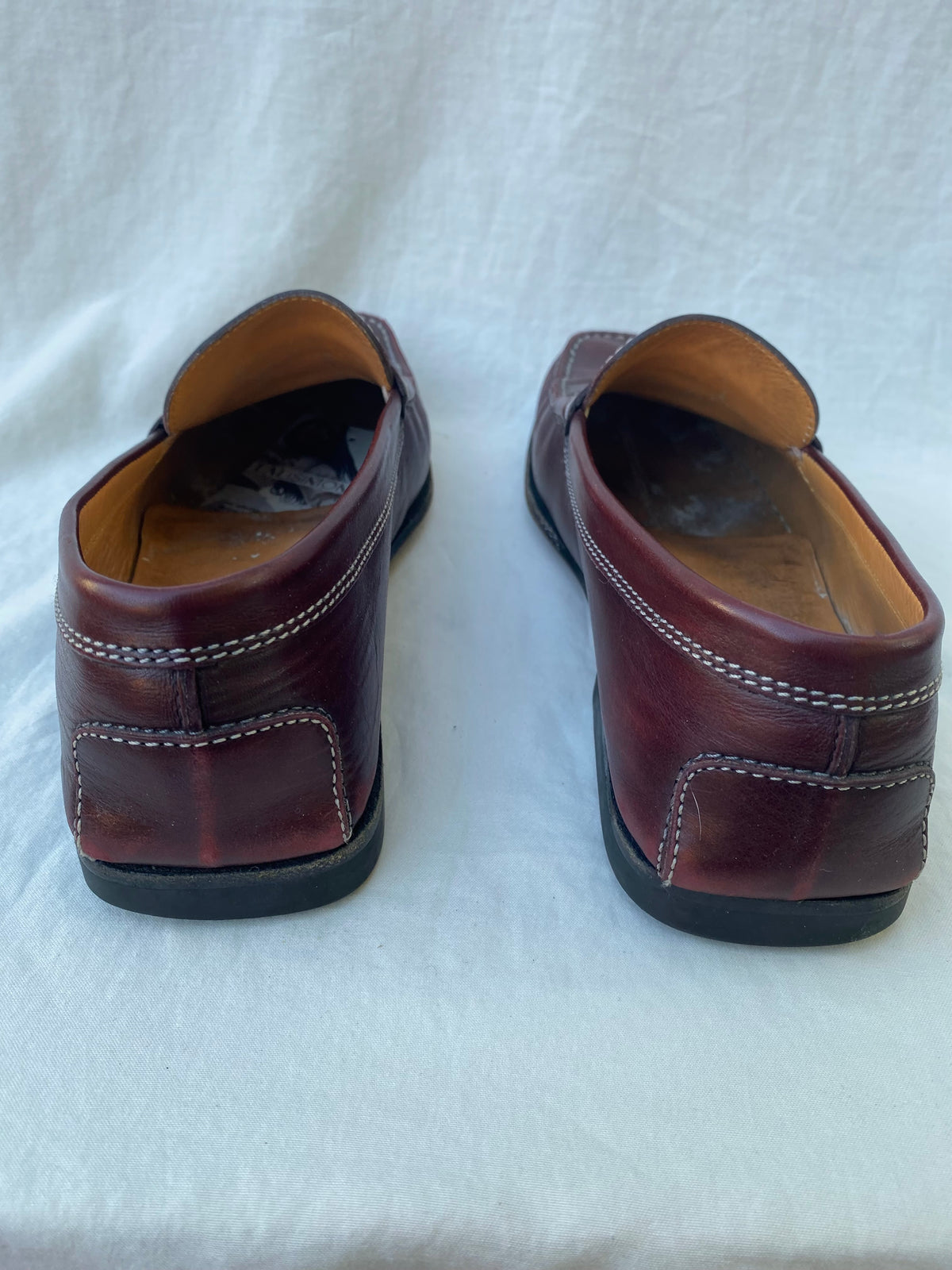 Back view of oxblood leather Tod's loafers showing the stitched heel patches and rubber heel pads