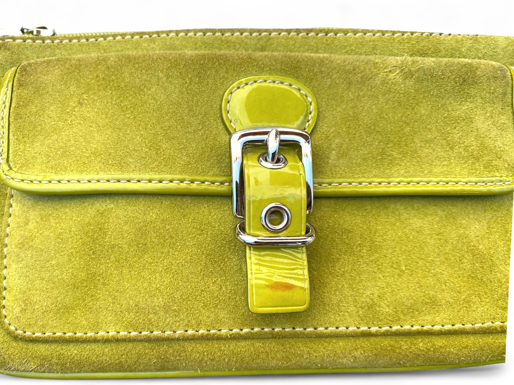 Image 3 (Close-Up of Buckle):
Close-up of the Coach wristlet front pocket with patent leather buckle strap and minor mark on the buckle.