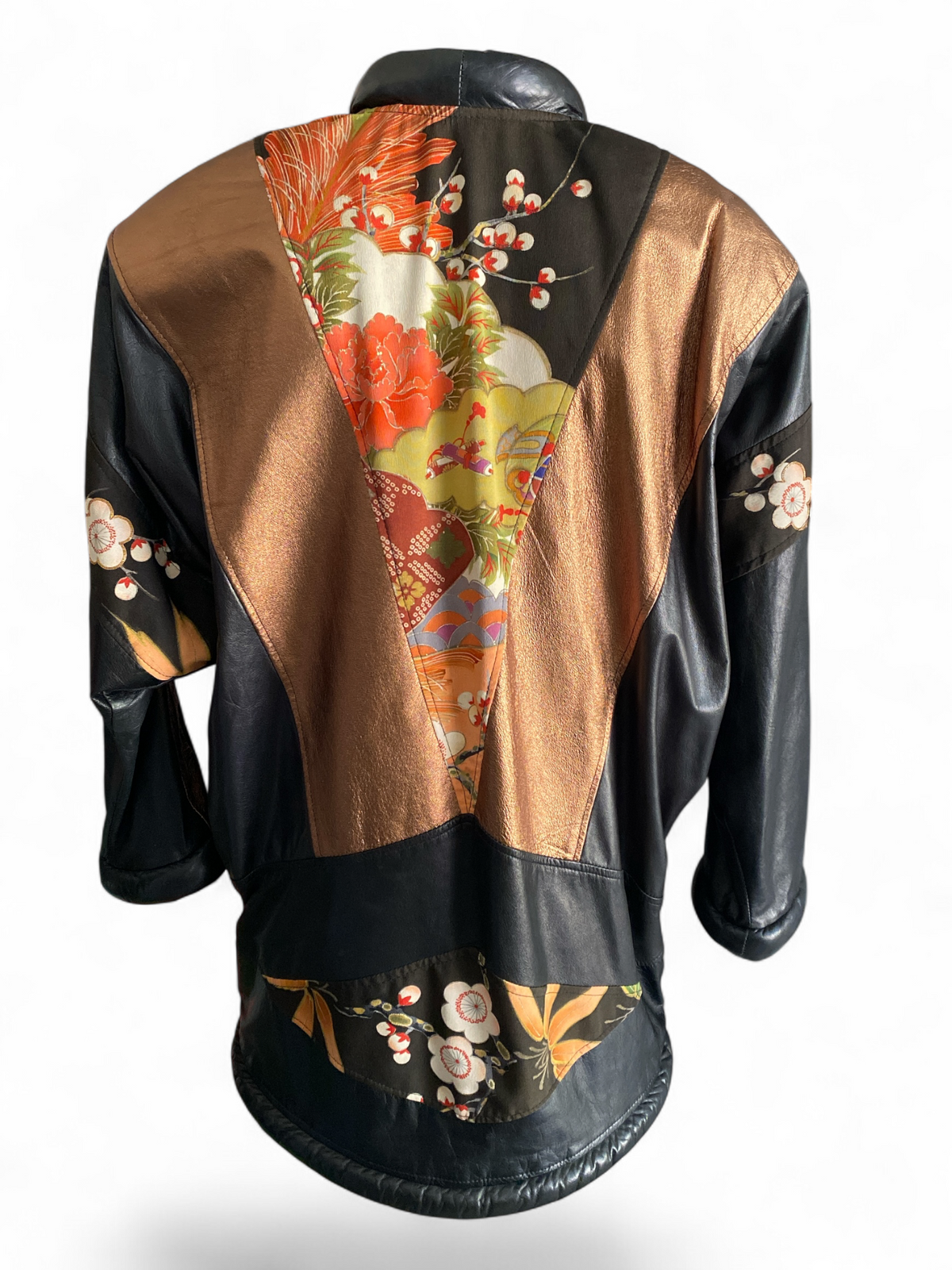 Opulent leather kimono jacket laid flat and open, showing the silk kimono floral panels, bronze leather color-blocking, rolled black leather collar and cuffs, with the woven brand tag visible at the neckline