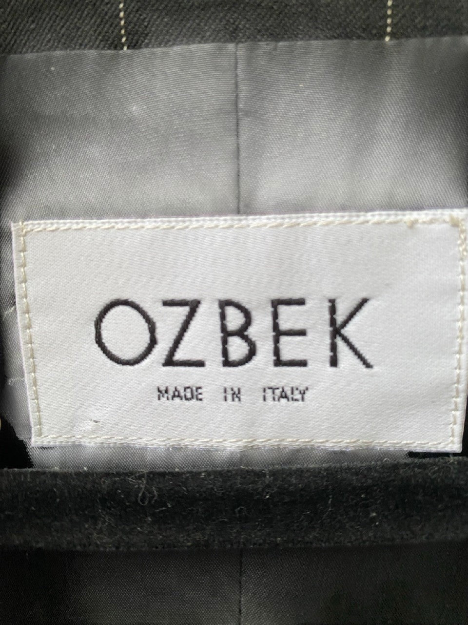 LaliSimone Ozbek black pinstripe jacket with fringe detail and "Made in Italy" label.