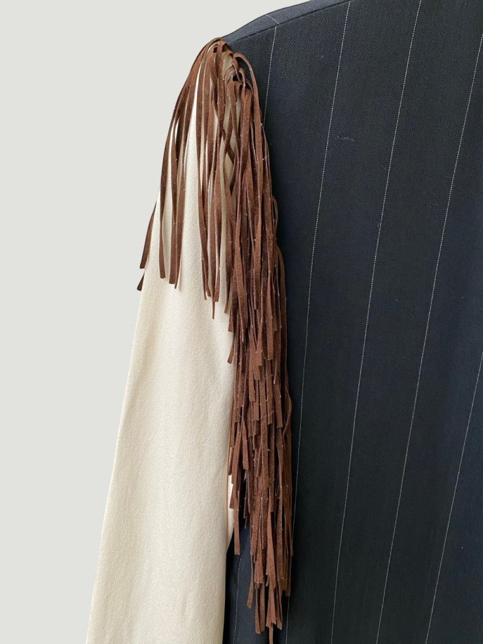 LaliSimone Ozbek jacket with pinstripe detail and brown suede fringe on the sleeve.