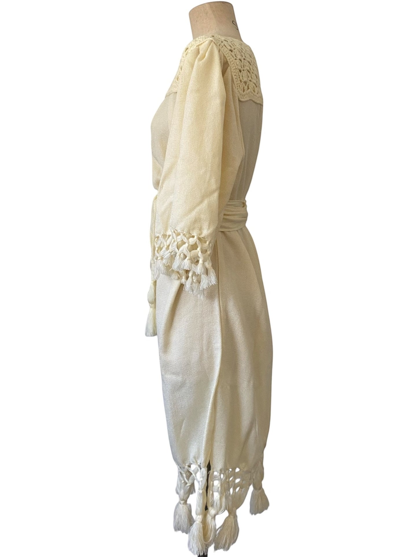 LaliSimone cream boho dress with crochet neckline, tasseled sleeves and hem, and matching belt.