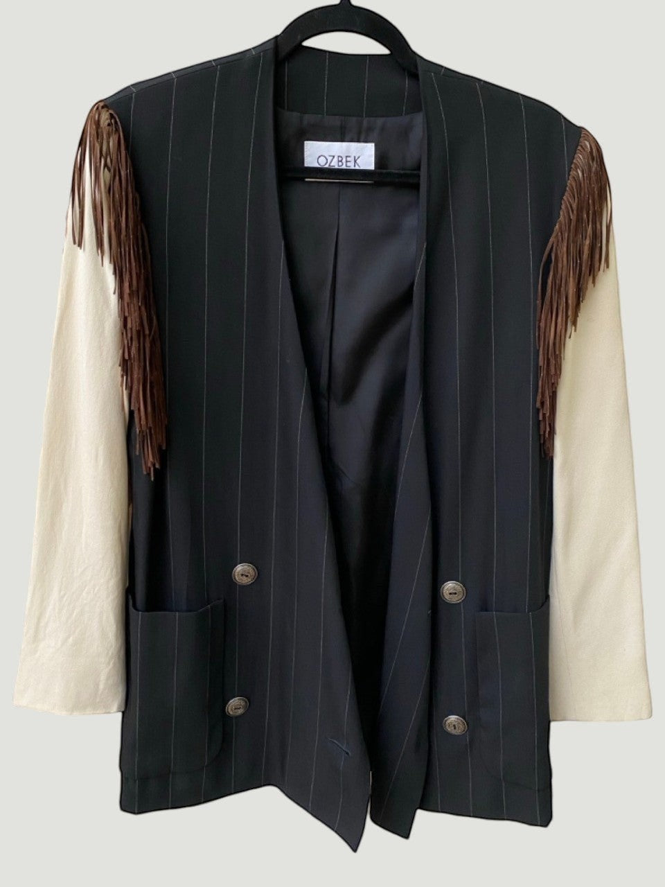LaliSimone Ozbek black pinstripe jacket with cream sleeves and brown fringe detail on shoulders.